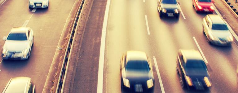 Blurry cars driving on road.
