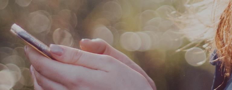 young woman holding mobile phone - side view of hands.