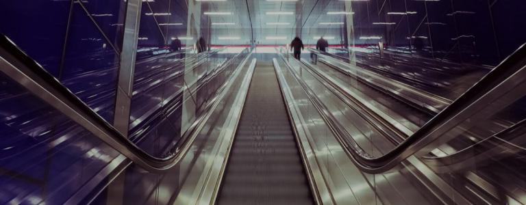 Looking up an escalator - centrally, Mostly dark and grey.